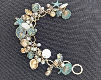 Pulsera con dijes de concha marina, color azul turquesa dorado, perlas.
