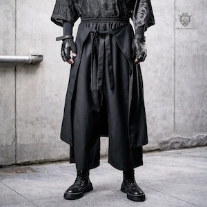 Könnte beinhalten: Schwarze, weit geschnittene Hose mit Wickeldesign und Bindverschluss. Die Hose wird mit einem schwarzen Oberteil und Stiefeln kombiniert. Das Bild zeigt auch schwarze Handschuhe. Das VENTAWEAR-Logo ist oben rechts sichtbar.