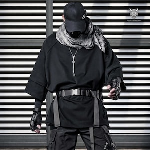 May include: A black baseball cap, a grey patterned scarf, a black short-sleeved shirt with a silver necklace, a black belt with a plastic buckle, and black fingerless gloves. The text VENTAWEAR is visible in the top right corner of the image.