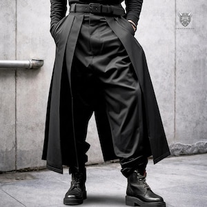 May include: Black trousers featuring a wide, skirt-like overlay panel that extends from the waist to the hem. The garment includes a black belt with a rectangular buckle and is paired with black leather lace-up boots. The fabric appears smooth.