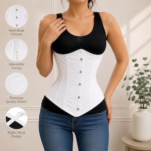 May include: A white corset featuring a steel busk closure with silver-toned buttons, adjustable back lacing, and a halter neck design. The garment is constructed from a smooth fabric and is shown over a black tank top and blue denim jeans.
