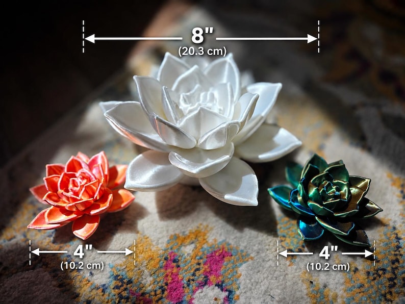 May include: Three succulent-shaped decorative objects. The central white succulent measures 8 inches in diameter. The orange succulent on the left and the dark green succulent on the right each measure 4 inches in diameter.