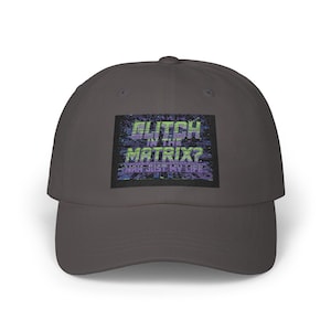 May include: A gray baseball cap with the text "Glitch in the Matrix? Nah Just My Life" in a pixelated design. The cap has a curved brim and a classic six-panel construction, suitable for casual wear.