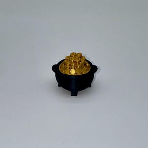 May include: A black pot filled with gold coins. The pot has a rounded shape with two handles and three small feet. The gold coins are circular and stacked inside the pot, creating a treasure theme.