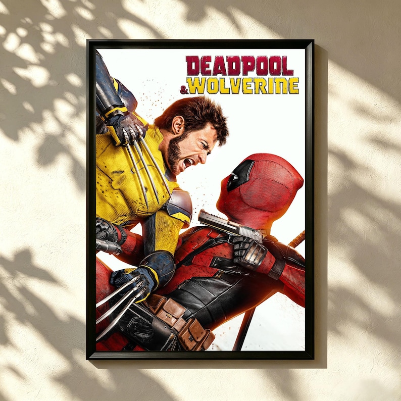 May include: Framed poster depicting Deadpool and Wolverine in a dynamic action scene. Deadpool, in a red suit and mask, aims a gun. Wolverine, in a yellow and blue suit, attacks with claws extended. The title "DEADPOOL & WOLVERINE" is at the top.