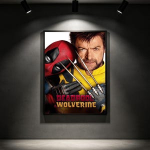 May include: Framed movie poster featuring Deadpool in a red mask and Wolverine with metal claws. The poster has the words "Deadpool & Wolverine" in red and gold. The background is a dark grey wall with spotlights.