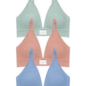 May include: Three soft bras in pastel colors: mint green, peach, and light blue. Each bra has a V-neck design with adjustable straps and a small rectangular label at the bottom. The bras are made of a textured fabric.
