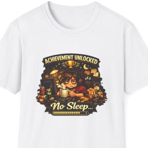 Puede incluir: Camiseta blanca con un diseño gráfico colorido. El diseño presenta el texto "Achievement Unlocked" y "No Sleep..." encima de una ilustración de dibujos animados de una persona con una taza de café, rodeada de elementos relacionados con los juegos.