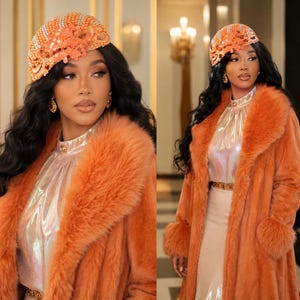 May include: An orange faux fur coat with a large collar and cuffs. The person is wearing a beaded orange head covering and a shimmering top. The outfit is accessorized with gold earrings and a belt. The background is a well-lit interior.