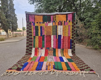 May include: A rectangular area rug featuring a vibrant, multi-colored geometric block pattern in shades of red, yellow, orange, green, blue, pink, and white. The rug has a thick, shaggy texture and includes a fringed edge at the bottom.