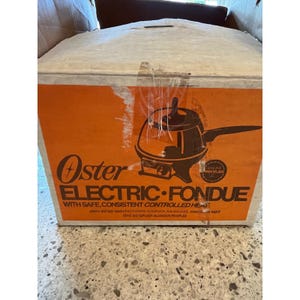 May include: A white and orange cardboard box for an Oster electric fondue pot. The front features a graphic of the fondue pot, the text Oster ELECTRIC FONDUE WITH SAFE, CONSISTENT CONTROLLED HEAT, and the John Oster Manufacturing Company address.