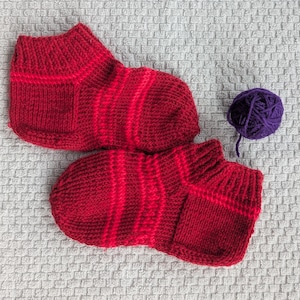 May include: A white ceramic mug with a black handle and the text "But First, Coffee" in a black, handwritten-style font. The mug is on a white surface.