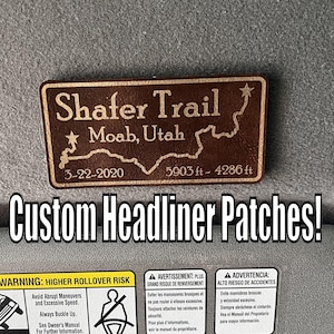 May include: A brown headliner patch with the text "Shafer Trail Moab, Utah 3-22-2020 5903 ft - 4286 ft". The patch is rectangular with a map outline. The image also includes the text "Custom Headliner Patches!"