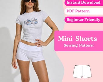 Op de afbeelding: Een lichtgrijs t-shirt met korte mouwen met een Amalfi Italia grafische print en effen witte mini-shorts. De afbeelding bevat de tekst: Instant Download, PDF Pattern, Beginner Friendly, Mini Shorts Sewing Pattern en een lijntekening.