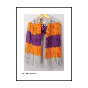 May include: A crochet scarf featuring horizontal stripes in light grey, bright orange, and deep purple. The scarf has an open, lacy stitch pattern and is displayed on a wooden hanger. The text "Skill Level: Intermediate" is printed below.