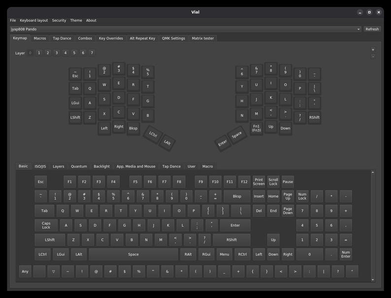 May include: A dark gray software interface titled Vial displaying a split ergonomic keyboard layout on the top half and a standard full-size keyboard layout on the bottom half, with various menu tabs including Keymap, Macros, and QMK Settings.