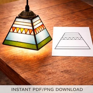 Op de afbeelding: Een piramidevormige glas-in-loodlamp met een messing armatuur hangt boven een houten oppervlak. De lamp heeft een geometrisch ontwerp met witte, oranje, gele en groene glazen panelen. Een papier met een lampomtrek ligt naast de lamp. De tekst onderaan luidt "INSTANT PDF/PNG DOWNLOAD".