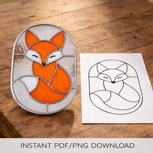 Puede incluir: Un diseño de zorro en vidriera en un marco ovalado. El zorro es naranja con detalles blancos, sobre un fondo blanco texturizado. Un dibujo lineal en blanco y negro del zorro está al lado.
