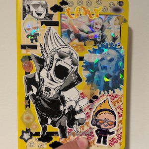 May include: A yellow notebook covered in stickers and illustrations. The notebook features various anime-style character stickers, including a large black and white image of a character with sunglasses. Other stickers include holographic accents and text that reads "POP MYSTERY POP".