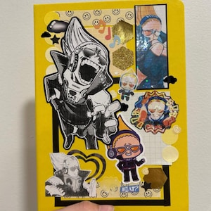 Puede incluir: Un cuaderno amarillo decorado con pegatinas de estilo anime. Las pegatinas incluyen una gran ilustración en blanco y negro de un personaje con gafas de sol, figuras de dibujos animados más pequeñas y detalles de purpurina dorada. La palabra "WHAT?" es visible.