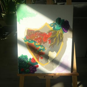 May include: An abstract painting on canvas, featuring a shield shape with a gold outline. The shield is filled with red and green brushstrokes, and adorned with colorful flowers. The artwork is displayed on a wooden easel.