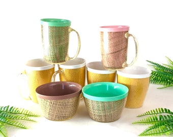 Pode incluir: Conjunto de seis canecas vintage com um padrão de juta tecida. As canecas são de várias cores, incluindo verde, rosa, branco e amarelo. As canecas estão empilhadas umas sobre as outras.
