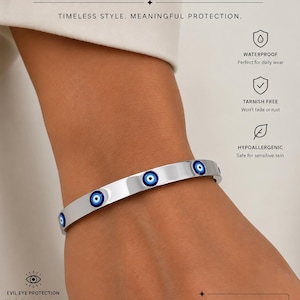 May include: A silver-toned stainless steel bangle bracelet featuring multiple circular blue, white, and black evil eye charms embedded along the band. The text on the image reads Evil Eye Protection, Stainless Steel Bracelet, and lists features.