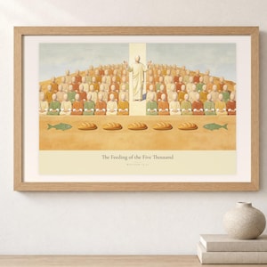 Shelf mockup of The Feeding of the Five Thousand in a light oak frame resting on a pale wood surface beside stacked neutral books and a rounded ceramic vase. The framed print shows Christ raised on the centre axis above a seated hillside crowd, with loaves and fish laid out along the foreground. Cream matting, soft wall texture, and natural light present the horizontal Bible artwork at an easy domestic scale.