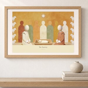 Shelf mockup of The Nativity in a light oak frame resting on a pale wood surface beside stacked neutral books and a rounded ceramic vase. The framed print shows the wrapped child in a low manger between two kneeling figures, beneath a single star. Cream matting, soft wall texture, and natural light present the horizontal Bible artwork at an easy domestic scale.