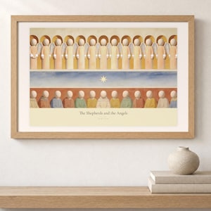 Shelf mockup of The Shepherds and the Angels in a light oak frame resting on a pale wood surface beside stacked neutral books and a rounded ceramic vase. The framed print shows a row of angels above shepherds and their sheep, with a star set between the two groups. Cream matting, soft wall texture, and natural light present the horizontal Bible artwork at an easy domestic scale.