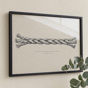 Premium close-up of the Cord of Three Strands frame slightly angled, with a soft eucalyptus sprig in the corner and clear glass reflection across the artwork. Hand-drawn Ecclesiastes 4:12 Christian wedding bible verse wall art, instant digital download.