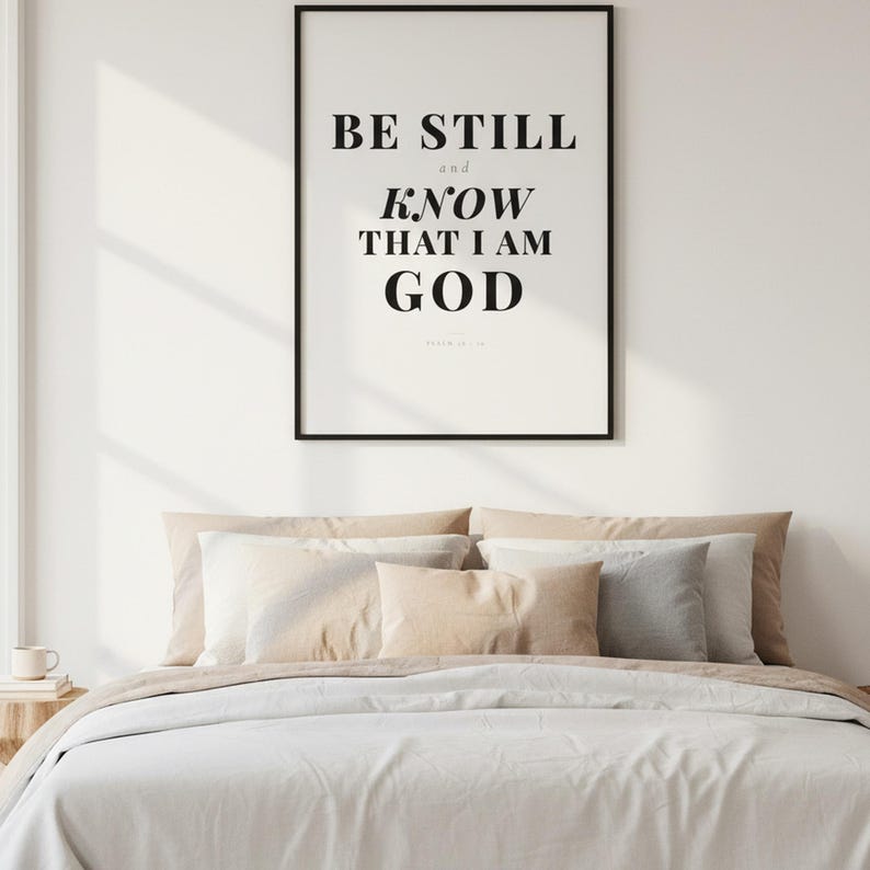 Psalm 46 10 Wall Art Be Still and Know That I Am God Scripture Print Christian, — "Be still and know that I am God. I will be exalted among the nations", in contemporary bold serif typography in black on clean white background, photographed in beautiful close-up detail showing the premium glass frame reflection, the crisp typography and the intricate artistic details of the design
