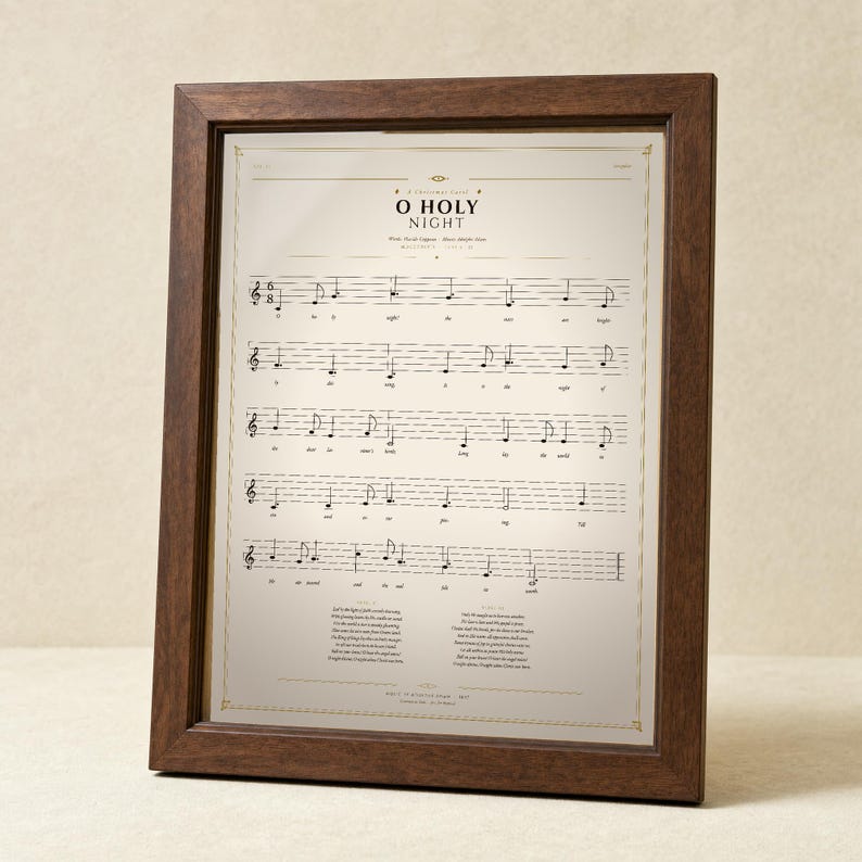 O Holy Night vintage sheet music print in a solid walnut frame, frontal studio shot on a cream backdrop with soft top-left key light and gentle glass reflection. Classical Christmas hymn wall art digital download from TheFramedVerse — single hymnal page reproduction of the beloved carol in warm sepia, cream, and soft black tones.