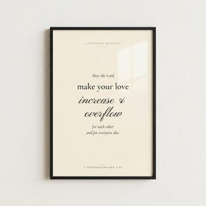 1 Thessalonians 3:12 'May the Lord Make Your Love Increase' Christian wedding wall art print in thin black metal frame, frontal view on off-white textured wall, modern minimalist styling with soft top light and gentle shadow below frame, e-commerce hero photograph, instant download from TheFramedVerse