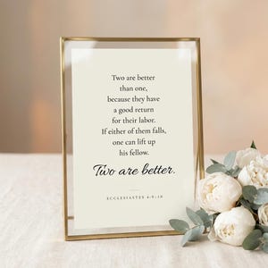 Ecclesiastes 4:9-10 'Two Are Better Than One' wedding scripture print in elegant brass-edged glass float frame with glass reflections, beside white peonies on cream linen. Botanical romantic Christian wedding wall art, newlywed and anniversary print, bridal shower keepsake, instant digital download.