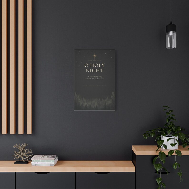 Elegant cream serif lettering spells O Holy Night among glowing golden stars, while shadowy evergreen trees border the textured charcoal paper. The dark black, cream, and gold artwork references the beloved Christmas carol and Luke 2:11 and is printed on stretched canvas. An alternate angle provides a clear product view of the wrapped canvas construction and dramatic vintage design.