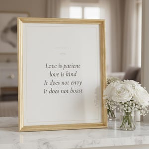Christian Wedding Wall Art Set of 3 Bible Verse Prints Love Is Patient, — "Love is patient, love is kind. It does not envy, it does not boast", in romantic wedding typography with elegant calligraphy, delicate gold ornamental accents on warm blush background, photographed in detailed close-up view showing the premium glass frame, crisp typography and intricate artistic details that make this