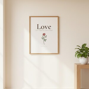 Love Fruit of the Spirit Christian wall art print featuring Galatians 5:22, with beautiful red rose botanical illustration, in minimalist botanical watercolor illustration on warm cream background with elegant serif typography, styled on a wooden floating shelf next to a ceramic vase with dried eucalyptus, creating a warm and inviting Christian home decor vignette