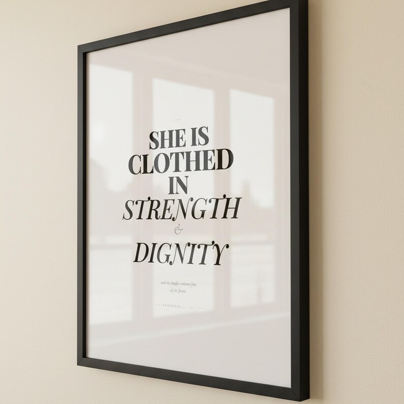 Proverbs 31 25 Wall Art She is Clothed in Strength and Dignity Scripture Print, — "She is clothed with strength and dignity, and she laughs without fear of the future", in elegant Mother's Day design with soft pink watercolor botanical flowers and graceful serif typography, showcased in an elegant contemporary home interior with curated decor elements