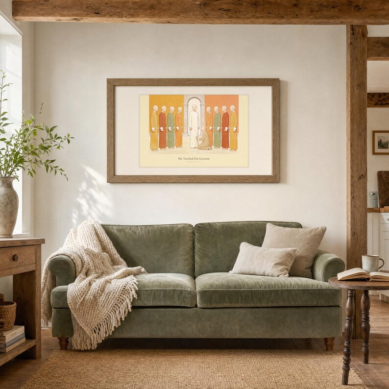 She Touched His Garment Matthew 9:20-22 print in a warm wood frame hanging above a sage green velvet sofa with a cream knit throw and linen pillows, exposed wood beams, potted greenery, and a side table with coffee and an open book, farmhouse Christian living room, digital download from TheFramedVerse