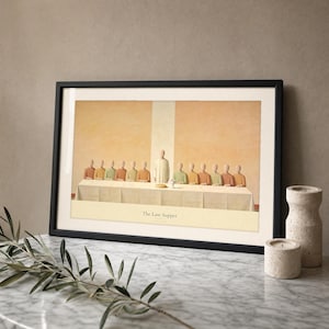 The Last Supper modern Christian print in a thin black frame with a visible glass front, leaning on a Carrara marble surface with a single olive branch casting a soft shadow at the left and two votive candles at the right. Warm beige plaster backdrop, bright morning light and a clean reflection across the glass. Digital download from TheFramedVerse on Etsy.