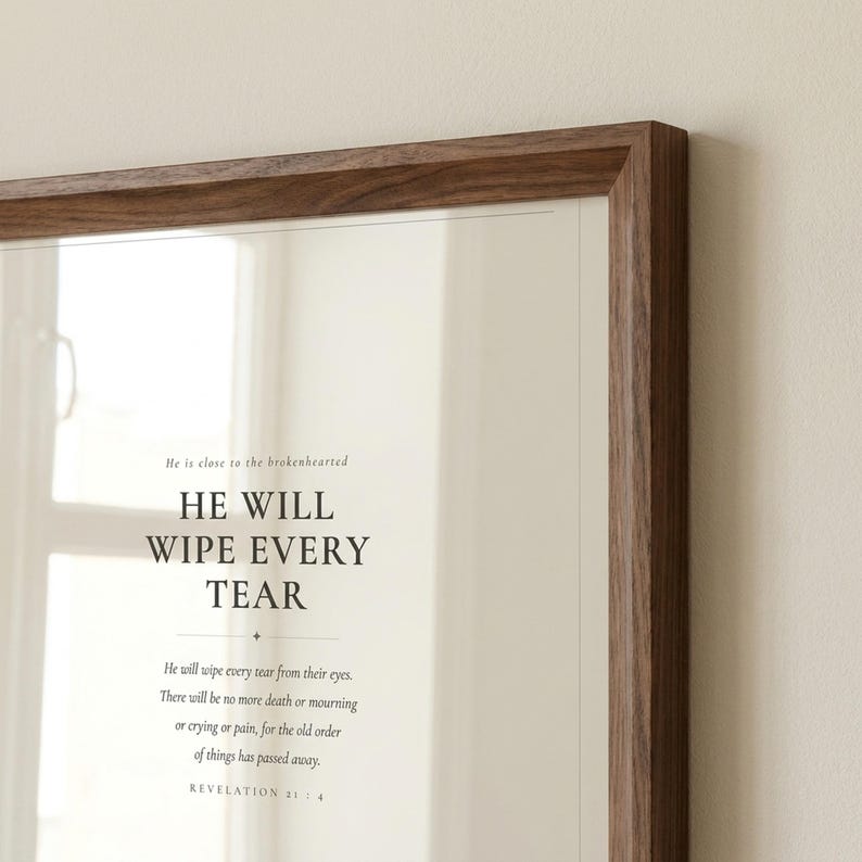 Straight front view of the complete artwork in a clean frame, making the typography and full composition easy to see. The He Will Wipe Every Tear artwork presents Revelation 21:4 in minimalist black typography on warm beige. This Revelation 21:4 print suits a sympathy gift, memorial space, prayer room, bedroom, or comforting Christian home as printable digital wall art.