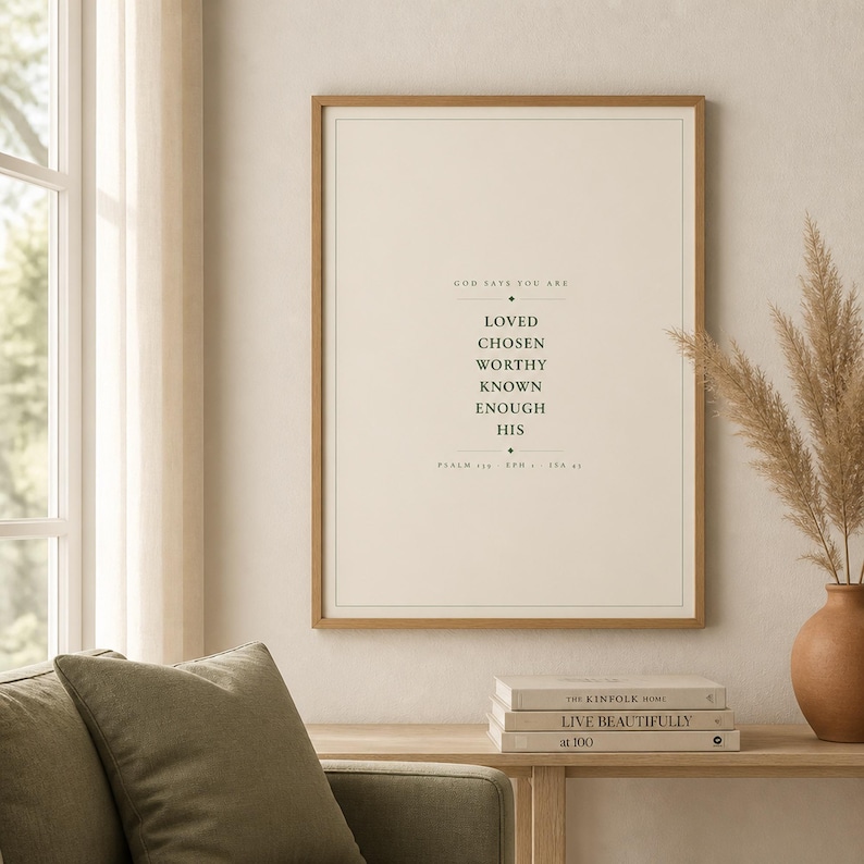 Warm lifestyle room with the framed design on a soft cream wall beside neutral decor and natural window light. The God Says You Are Loved Chosen Worthy Known Enough His artwork uses minimalist forest green typography on warm beige. This Christian affirmation print suits a nursery, baptism gift, baby dedication, bedroom, or encouraging faith centered space as digital wall art.