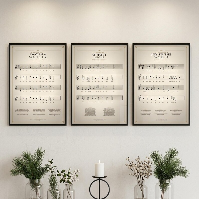 Christmas Hymns Set of 3 vintage hymn prints — Away in a Manger, O Holy Night, Joy to the World — in thin black metal frames, frontal view on off-white textured wall, modern classical Christmas gallery wall arrangement, soft top light with gentle shadow, holiday christian wall art digital download TheFramedVerse