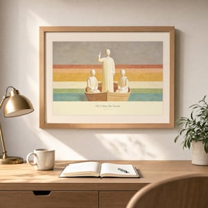 Desk mockup of He Calms the Storm in a light oak frame above a wooden workspace with a brass lamp, ceramic mug, open notebook, pen, and leafy plant. The artwork shows Christ standing in a wooden boat with a raised hand above calm layered water. Angled sunlight, neutral styling, and cream matting place the Bible story print in a quiet study or home office setting.