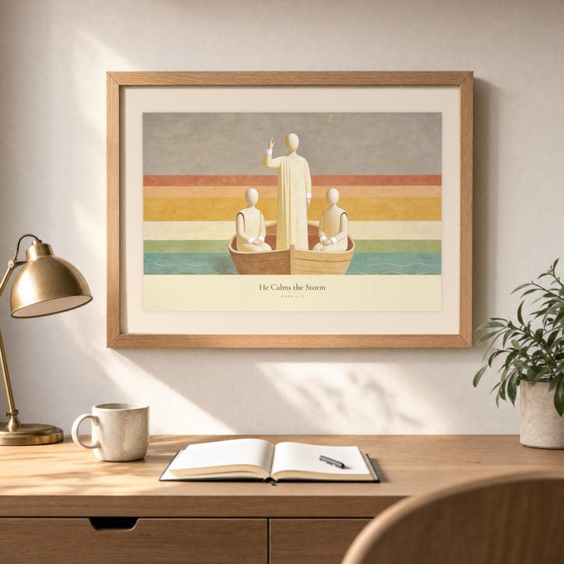 Desk mockup of He Calms the Storm in a light oak frame above a wooden workspace with a brass lamp, ceramic mug, open notebook, pen, and leafy plant. The artwork shows Christ standing in a wooden boat with a raised hand above calm layered water. Angled sunlight, neutral styling, and cream matting place the Bible story print in a quiet study or home office setting.