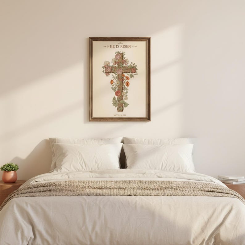 William Morris He is Risen Cross Print – Floral Easter Christian Decor, in vintage William Morris Arts and Crafts botanical style with ornate floral border on aged cream parchment, hanging above a cozy bed in a peaceful bedroom setting, creating an inspiring and calming atmosphere for morning devotions and evening prayer