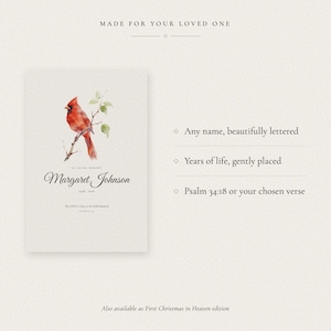 Personalization explanation graphic showing where the loved one's name and memorial year appear on the First Christmas in Heaven print. A labeled example displays Margaret Johnson and 2026 beneath the snowy cardinal illustration. The guide makes clear that buyers provide one name and one year, which are carefully centered within the seasonal remembrance design before delivery.