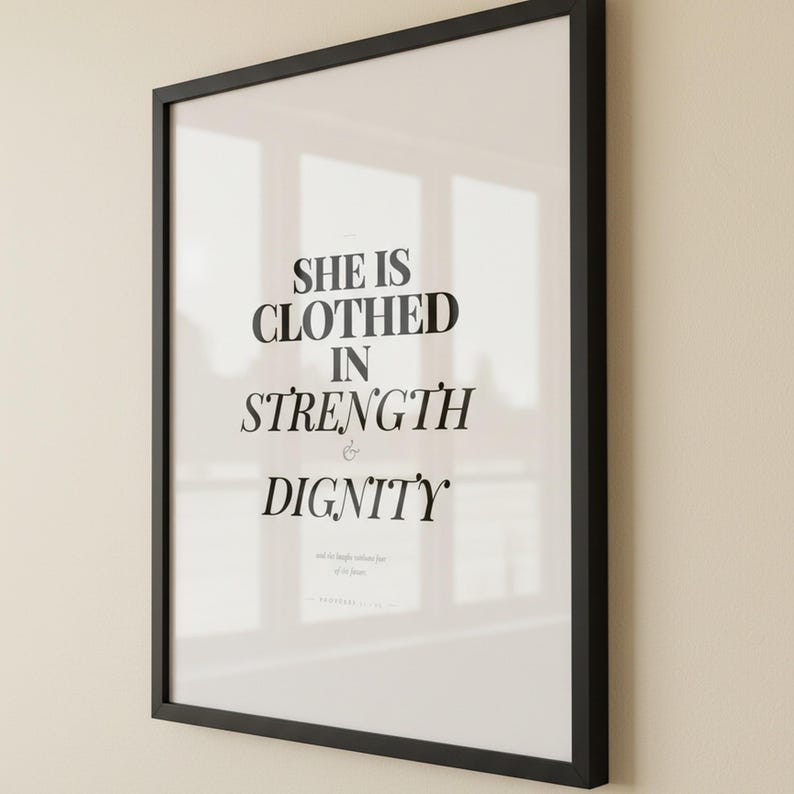 Proverbs 31 25 Wall Art She is Clothed in Strength and Dignity Scripture Print, — "She is clothed with strength and dignity, and she laughs without fear of the future", in elegant Mother's Day design with soft pink watercolor botanical flowers and graceful serif typography, presented as an elegant flat lay on white marble with a fountain pen and eucalyptus sprig