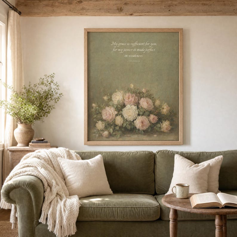 Grace Is Sufficient 2 Corinthians 12 9 vintage oil painting print framed in oak hung centered above a sage velvet sofa with cream knit throw and linen pillows, side table with ceramic mug and open bible, cottage farmhouse Christian living room with exposed wooden beam, soft afternoon window light, instant download wall art TheFramedVerse Etsy